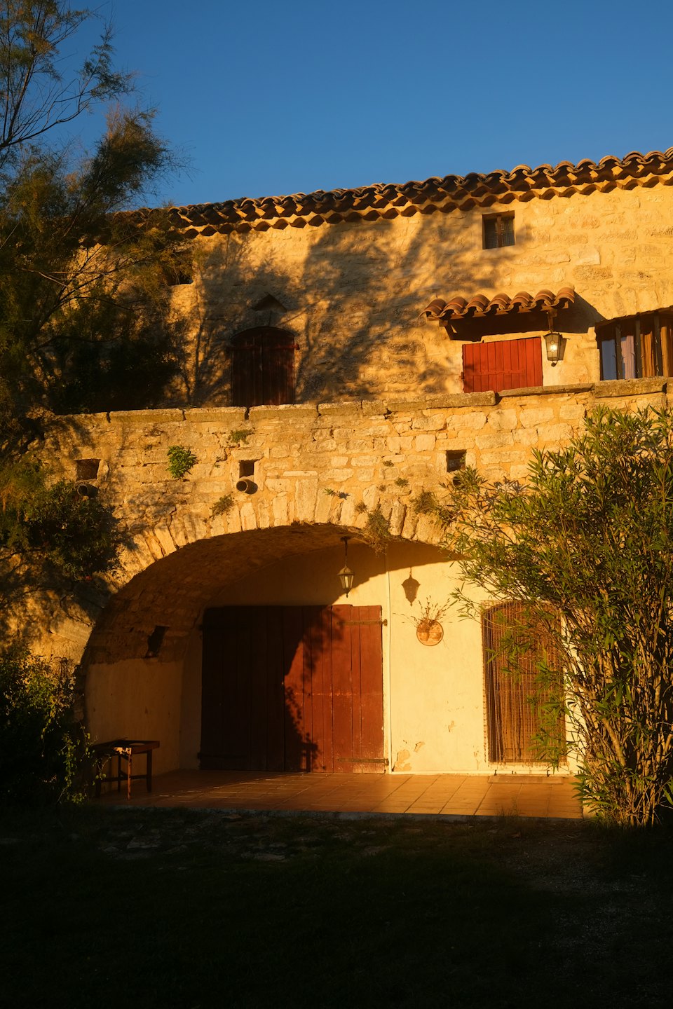 Rustic stone building with arched doorway at sunset.